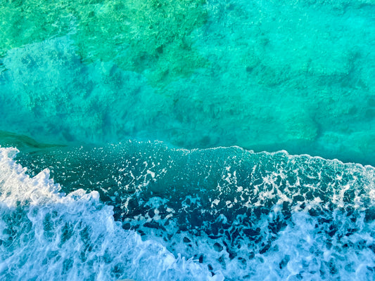 Waves crash upon the shore in shades of blue.