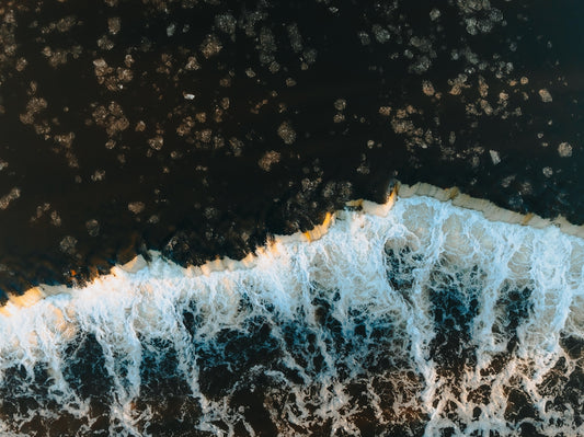 Aerial view of a breaking ocean wave at sunset