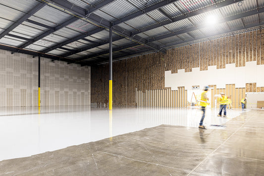 Two construction workers in a large empty warehouse