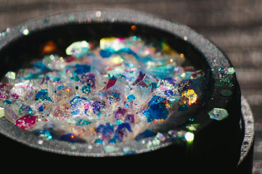 Macro view of iridescent blue and purple glitter flakes inside a black container